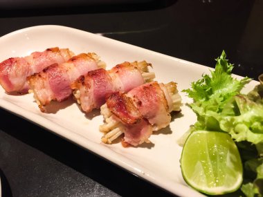 Altın iğne mantar ile ızgara domuz pastırması. İştah açıcı taze salata ve kireç ile bu