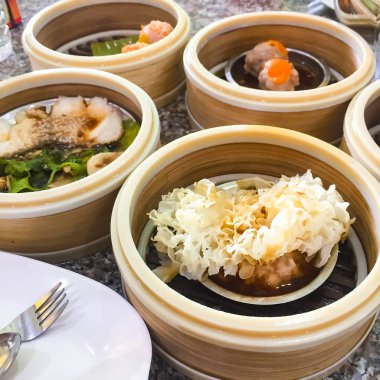 Dim sum , Bu buharda pişirilmiş popüler bir Çin gıda. Küçük bambu sepetindeler. Küçük ahşap bir sepet içinde düzenlenmiştir. Sağ alttaki resim loş sum olduğunu contai