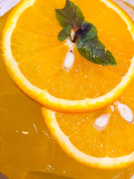 It is a close-up photo of orange juice in a glass. It has  ice cubes, sliced oranges and orange juice. Next is the beautiful flesh edible meat of orange that it can eat