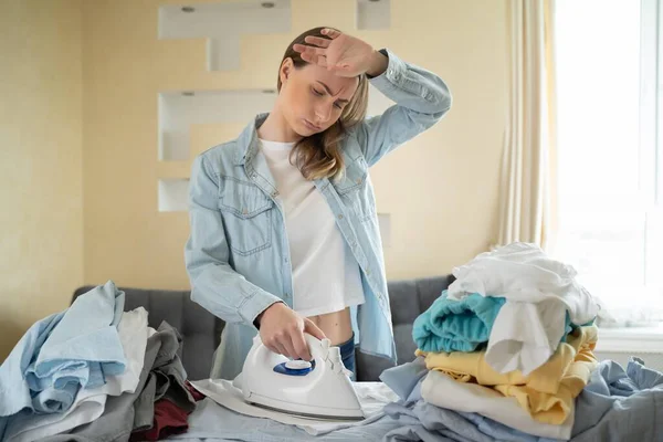 可悲的女人在家里熨烫衣服 — 图库照片