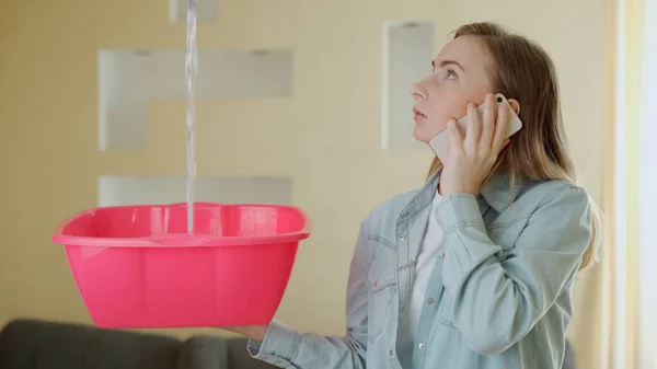 Upset household calling roof repair service while water leaking from ceiling — Stock Photo, Image