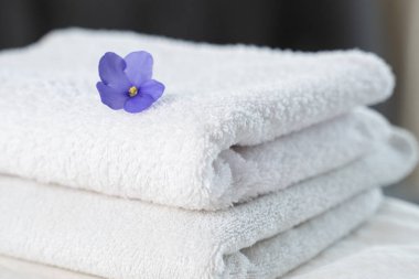 Masadaki spa kompozisyonu. Çiçekli iki tane kabarık banyo havlusu..