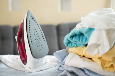 Elektrikli ütü ve ütü masasında giysi yığını