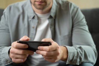 Mutlu, genç adam evde akıllı telefonla oyun oynuyor.