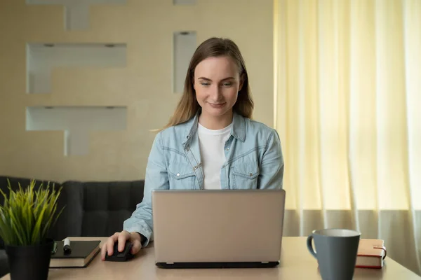 Gyönyörű fiatal nő dolgozik laptop számítógép, miközben ül a nappaliban — Stock Fotó