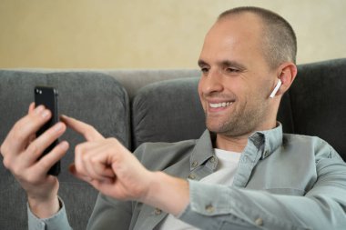 Adam evinde dinleniyor ve müzik dinliyor.