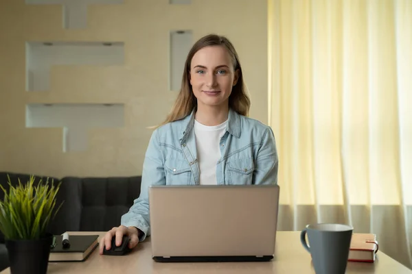 Gyönyörű fiatal nő dolgozik laptop számítógép, miközben ül a nappaliban — Stock Fotó