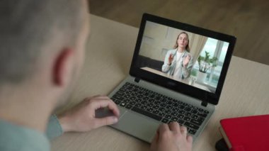 İş ortağıyla iş konuşmalarının arka planda laptopta video kullanarak iş projesini internette tartışırken görüntüsü.