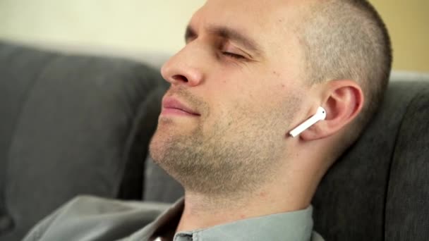 Мужчина расслабляется в своей квартире, слушая музыку — стоковое видео