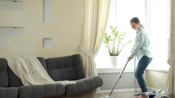 Vrouw het hebben van plezier schoonmaken huis met stofzuiger dansen thuis — Stockvideo