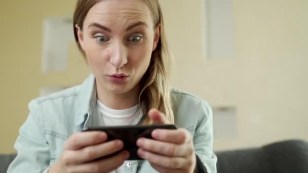 Vrolijke vrolijke, lachende jonge vrouw spelen smartphone spel, houden mobiele telefoon horizontaal als passerende race niveau, auto 's spel. — Stockvideo
