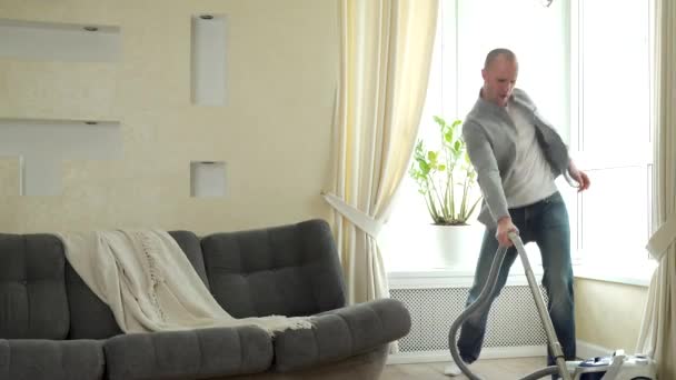 男人在吸尘器上玩就像在吉他上玩一样，在打扫房子的时候玩得很开心 — 图库视频影像