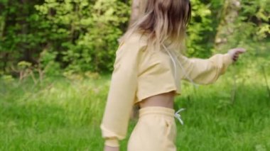 Parkta ağaçların arasında dönen güzel ve pozitif bir kız. Güzel bir gülümsemesi olan güzel bir kadın ormanda kameraya poz veriyor.