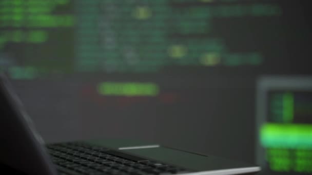 Bakgrund av olika datorutrustning med programmering kod på skärmar på bordet i mörka rummet, it-säkerhet koncept — Stockvideo