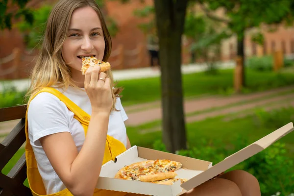 Młoda kobieta jedząca pizzę na ulicy — Zdjęcie stockowe