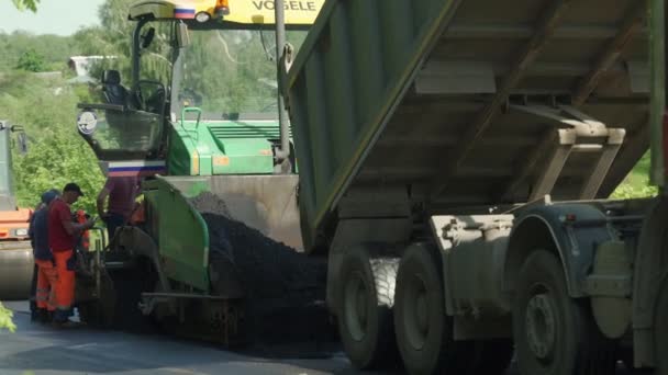 Pavimentadora de asfalto aplicando asfalto en la carretera. Un equipo utilizado para aplicar asfalto en la calle automáticamente. Un enorme equipo pesado poniendo asfaltos en la carretera. — Vídeo de stock