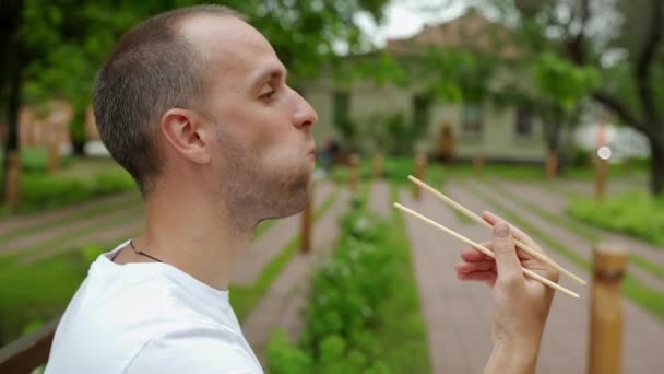 テイクアウト寿司を食べながら外に座っている男 — ストック動画