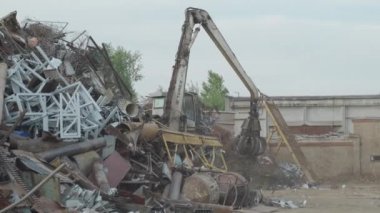 Makineye bak, hidrolik yakalama pençeli yükleyici manipülatörü eski çeliği topluyor, hareket ettiriyor, hurda metali.