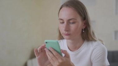 Çekici bir kadın evde oturup telefonla gülümsüyor. Mutlu hissediyorum. Cep telefonu ya da akıllı telefondan kadın mesajı.