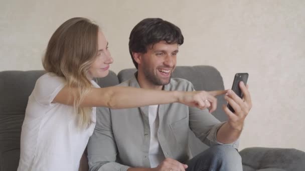 Sonriendo joven pareja abrazando mientras mira el teléfono inteligente. Pareja compartiendo redes sociales en el teléfono inteligente . — Vídeos de Stock