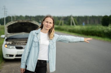 Genç bir kadının bozuk bir arabası var ve geçen bir arabayı yakalıyor.