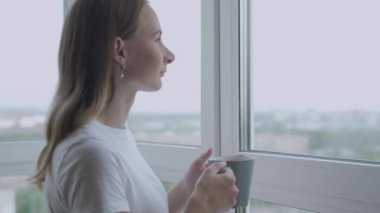 Yeni günün tadını çıkaran, dinlenmiş hisseden ve evde kahve içen bir kadın. Yavaş Hareket