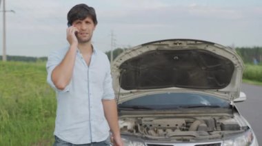 Bozuk arabanın yanında duran adam. Adam kaputu açtı ve motora baktı.. 
