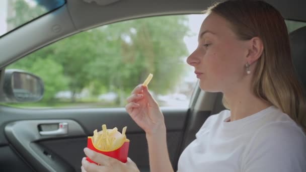 Kobieta je frytki w samochodzie. Ręce trzymające papierową torbę ze smażonymi ziemniakami fast food. — Wideo stockowe