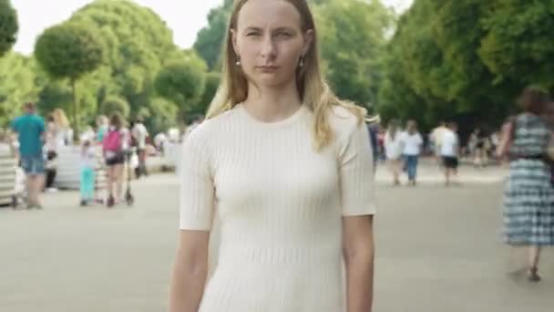 Time lapse of attractive woman standing in city center in busy street looking at camera wearing while crowds of people are walking by. — Video