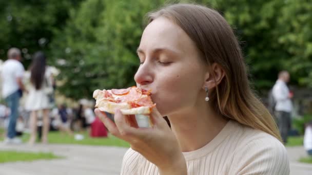 Женщина ест пиццу на открытом воздухе в парке — стоковое видео