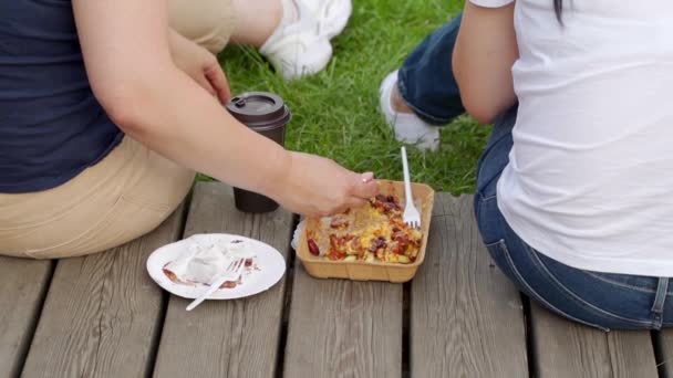 Gente sentada en el parque y comiendo comida rápida — Vídeos de Stock