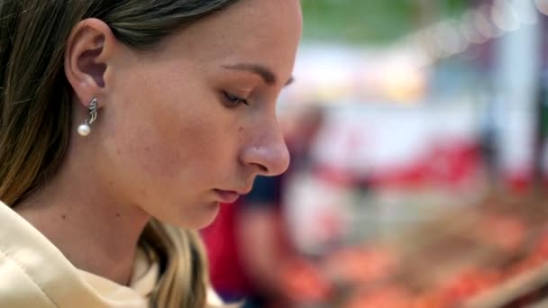 Vrouw ruikt tomaten tijdens het winkelen op de markt — Stockvideo