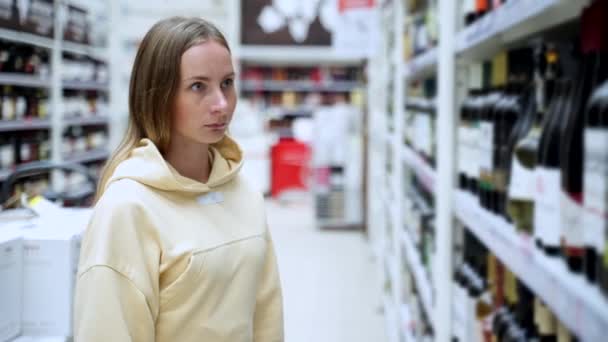 Frau wählt Wein im Supermarkt, Kunde wählt Produkt in den Regalen im Geschäft. — Stockvideo