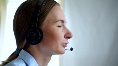 Masaüstü bilgisayarında kulaklık takılı müşteri destek aracı ya da çağrı merkezi müşteriyi telefonla desteklerken çalışır.
