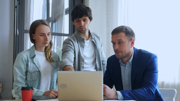 Les jeunes gens d'affaires qui travaillent avec un ordinateur portable et qui parlent de leur nouveau projet ensemble au bureau. — Photo