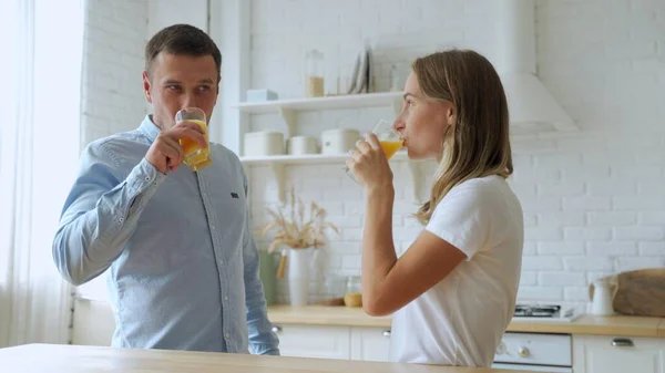 若いですカップル飲む新鮮なオレンジジュースでホームキッチン — ストック写真