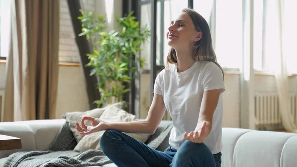 Atractiva joven mujer haciendo ejercicio y sentada en posición de loto de yoga — Foto de Stock