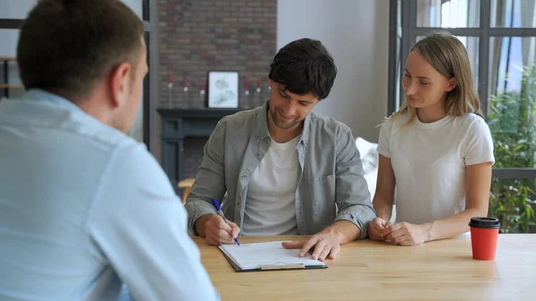 Paar unterschreibt Hypothekenvertrag, legt Unterschrift auf Kaufvertrag, schüttelt Makler bei Treffen mit Immobilienmakler die Hand. Zufriedene Kunden kaufen Immobilien, bekommen Schlüssel für neues Zuhause — Stockfoto