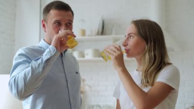 Genç çift evde taze portakal suyu içiyor.