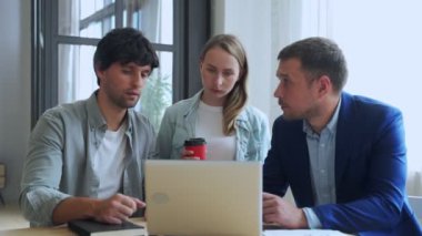 Genç iş adamları dizüstü bilgisayarla çalışıyorlar ve ofiste yeni projelerinden bahsediyorlar..