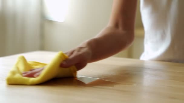 Femme au foyer essuyant le café ou le thé renversé d'une table de cuisine en bois. Femme utilisant une lingette nettoyante ménagère pour le nettoyage. — Video