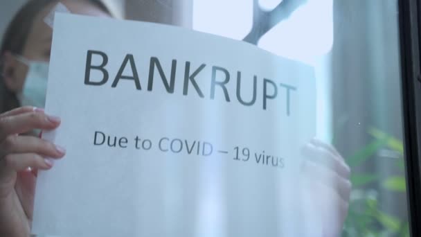 Žena pověsí oznámení o bankrotu na okno. Koncepce dopadu pandemie COVID-19 na podnikání. — Stock video