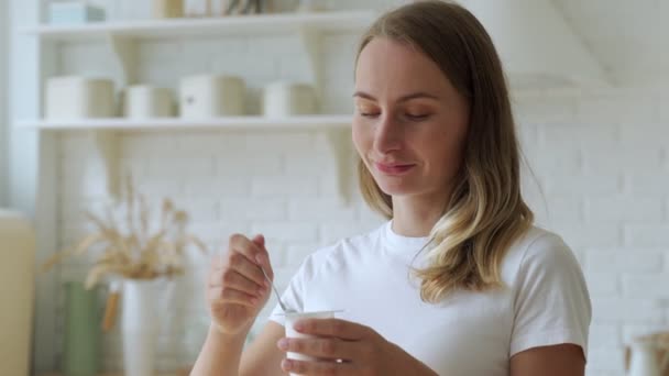 Portret van mooie jonge vrouw die thuis yoghurt eet. — Stockvideo