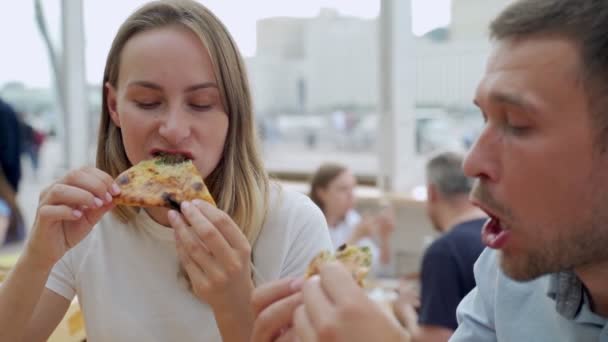 Paar isst Pizza im Freien und lächelt. Sie teilen sich Pizza in einem Café im Freien. — Stockvideo