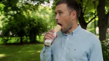 Aç adam sokakta sosisli yiyor.