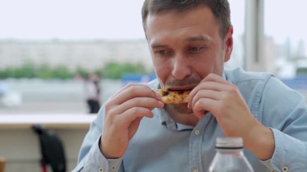 Красивый молодой человек ест пиццу на улице. — стоковое видео