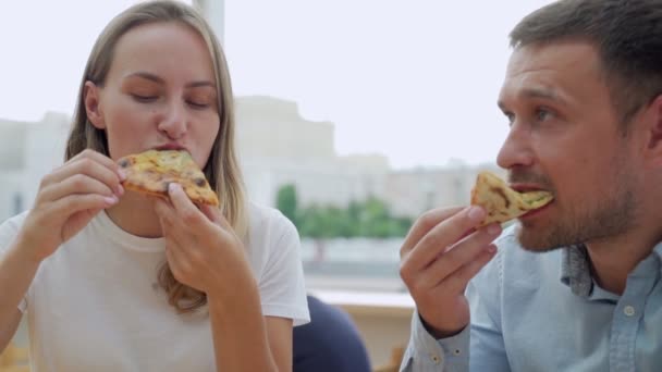 Молода пара їсть піцу на вулиці. Жінка і чоловік мають пікнік у парку. Концепція фаст-фуду . — стокове відео