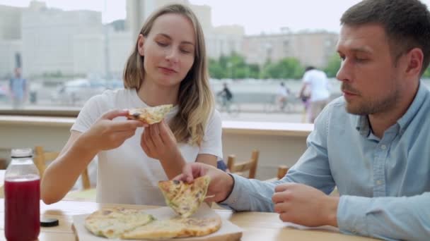 Pareja joven comiendo pizza afuera. Mujer y hombre de picnic en el parque. Concepto de comida rápida. — Vídeo de stock