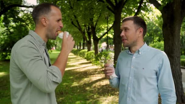 Dos amigos comiendo perritos calientes en la calle — Vídeos de Stock