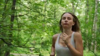 Genç bayan sporcu ormanda koşuyor.